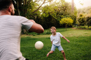 un papa joue au football avec son enfant