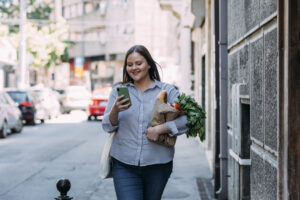 Jeune femme marchant sur un trottoir avec des légumes frais