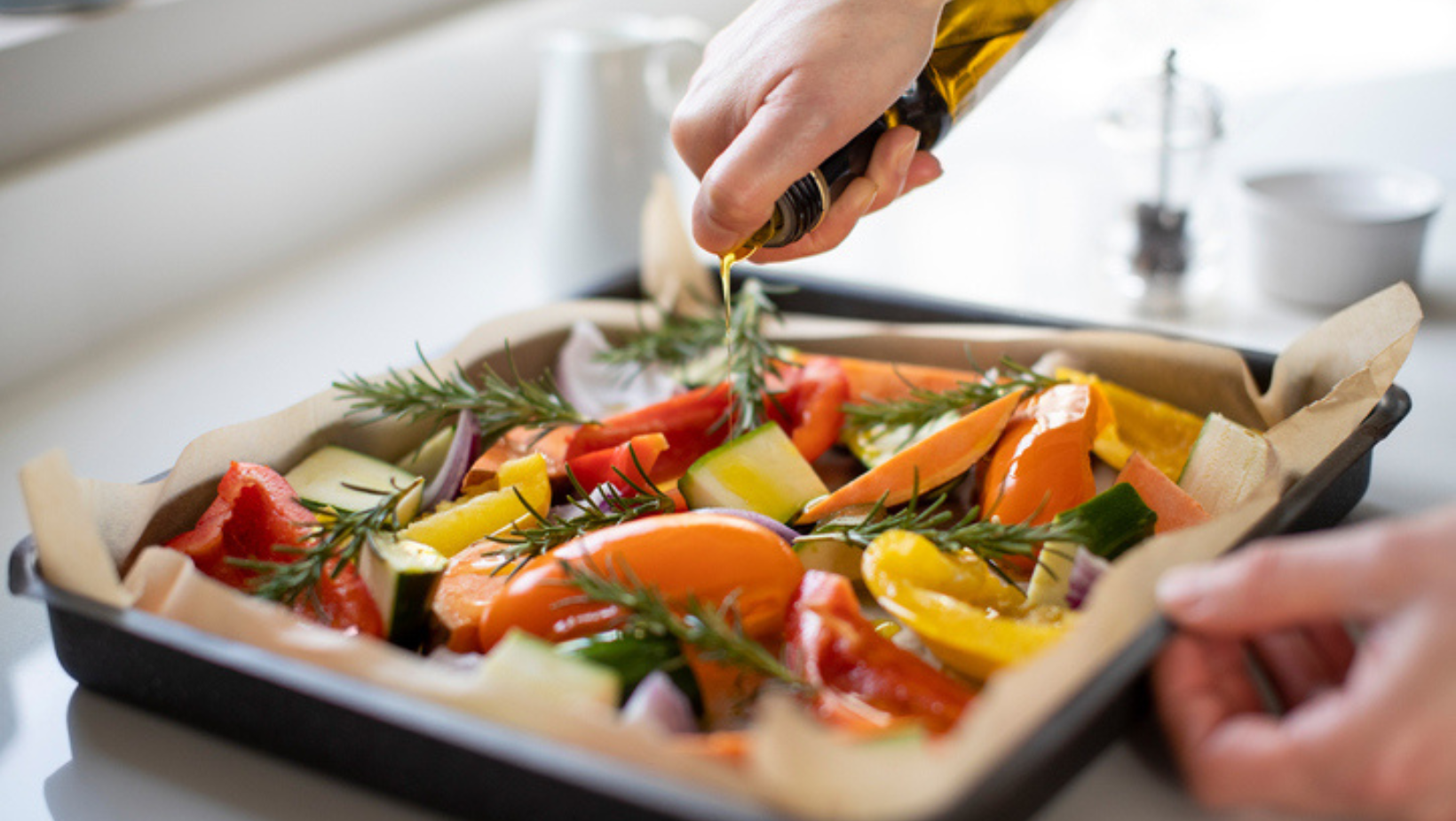 olijfolie gieten over bakplaat met kleurrijke groenten